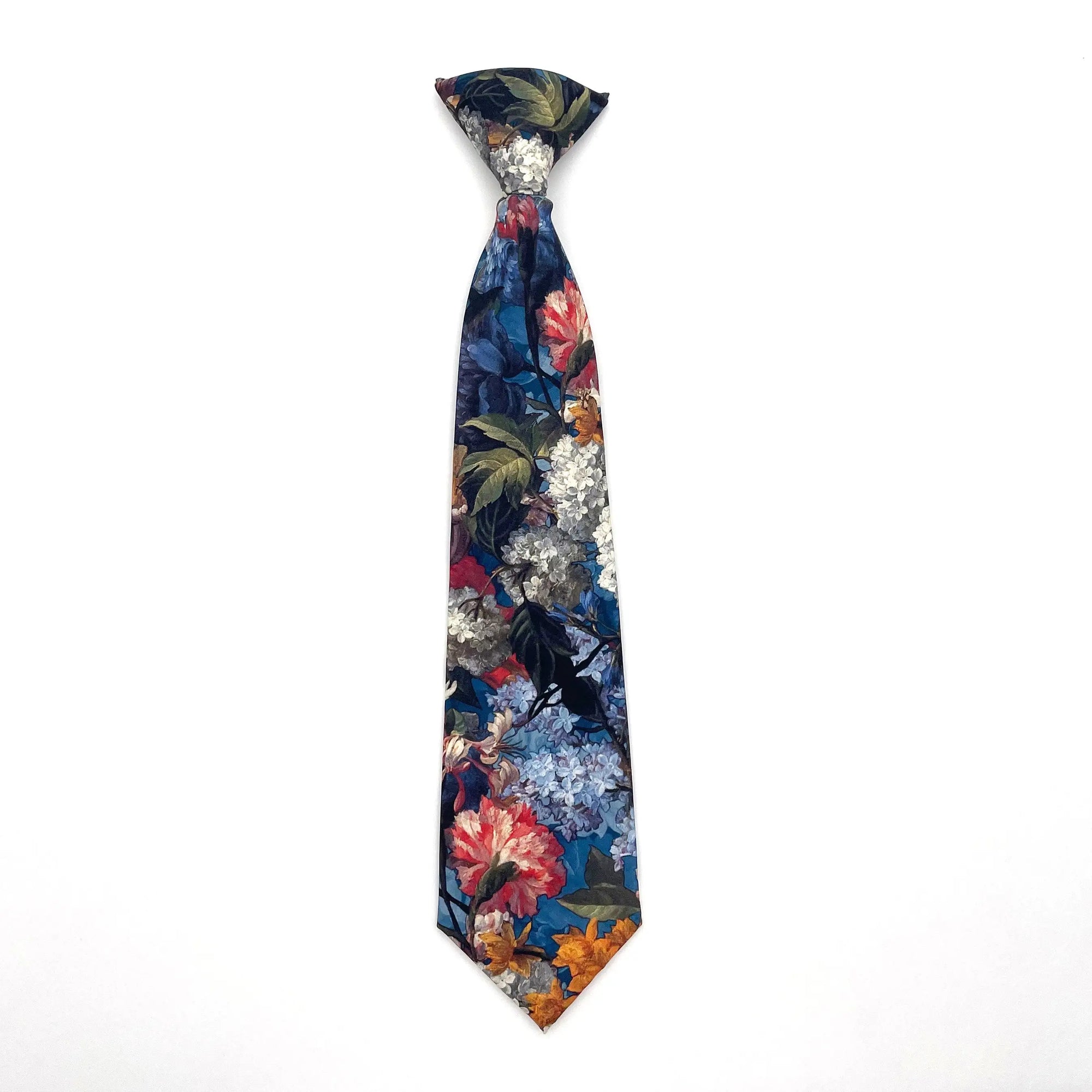 Blue Floral Boys Floral Clip On Tie 2.36 MYTIESHOP - HAMILTON-Blue Floral Boys Floral Clip On Tie - Clip on ties for kids Material: Cotton Approx Size: Color: Blue Max width: 6.5 cm / 2.4 inches 9-24 months 26 CM2-5 years 31 CM9-11 Years 43 CM To infuse a vibrant touch into your little one&#39;s attire, consider incorporating the Hamilton Boys Floral Clip On Tie. This versatile accessory is an excellent choice for various formal occasions, ranging from weddings to family gatherings. With its conveni