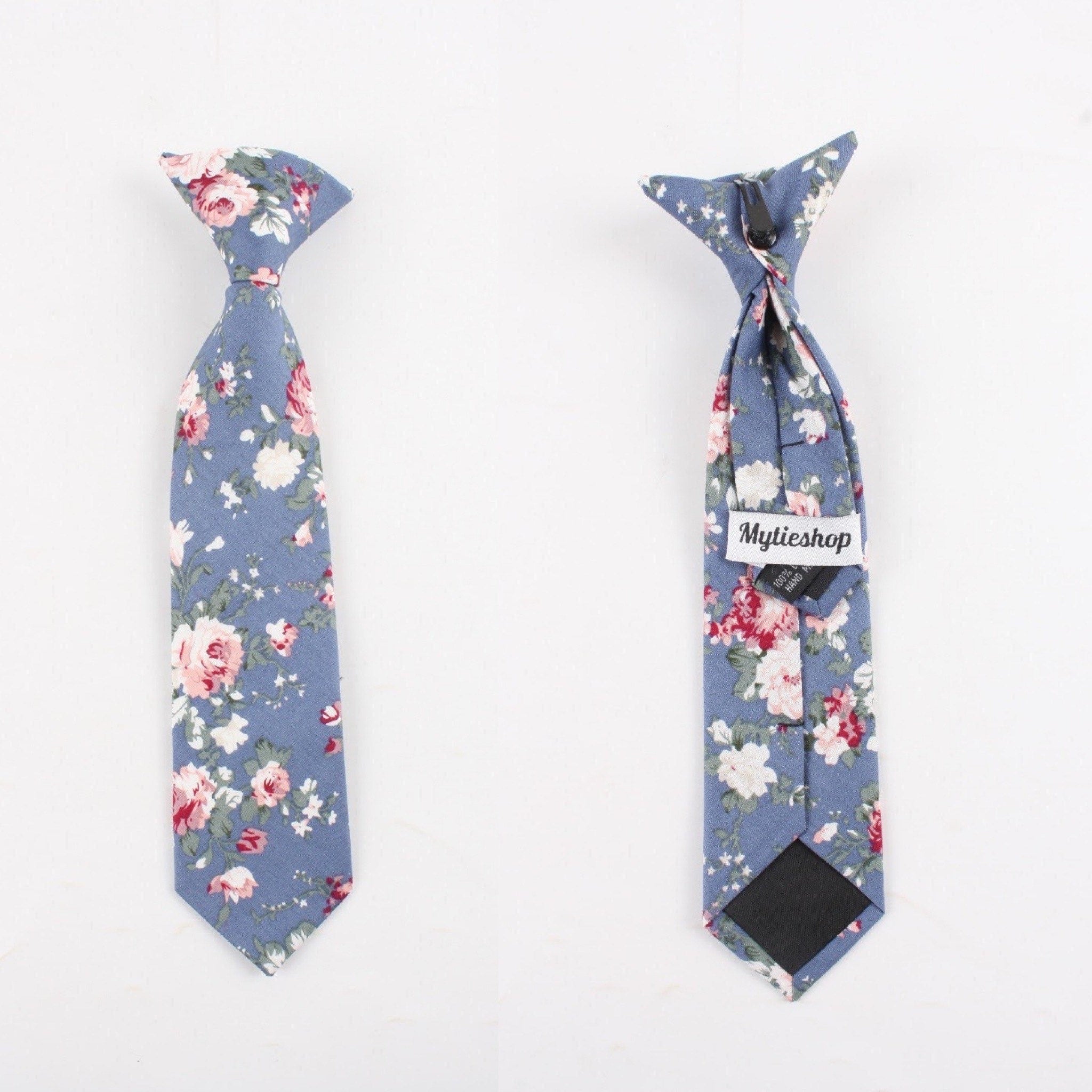 Boys Floral Clip On Tie 2.3&quot; NEIL-Boys Floral Clip On Tie Material:Cotton Blend Approx Size: Max width: 6.5 cm / 2.4 inches 9-24 months 26 CM2-5 years 31 CM9-11 Years 43 CM Get your little man looking sharp with this blue floral print tie. This dapper clip-on tie is perfect for any formal occasion, from weddings to christenings. The blue floral print is just the right amount of dainty, and the fit is tailored to fit boys of all ages. With a versatile style that can be dressed up or down, this ti